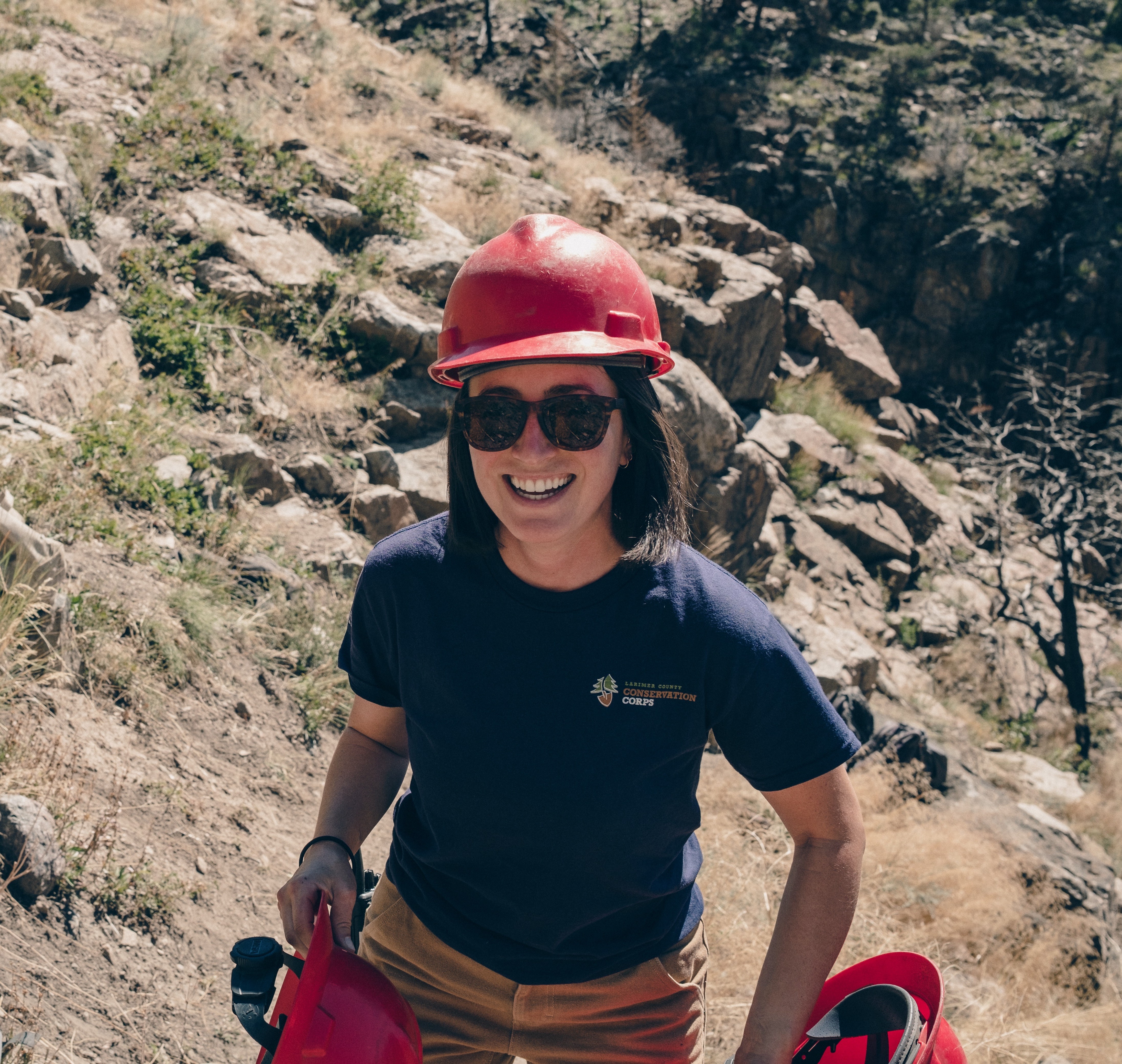 Kathryn Guy on rocky trail holding hard hats