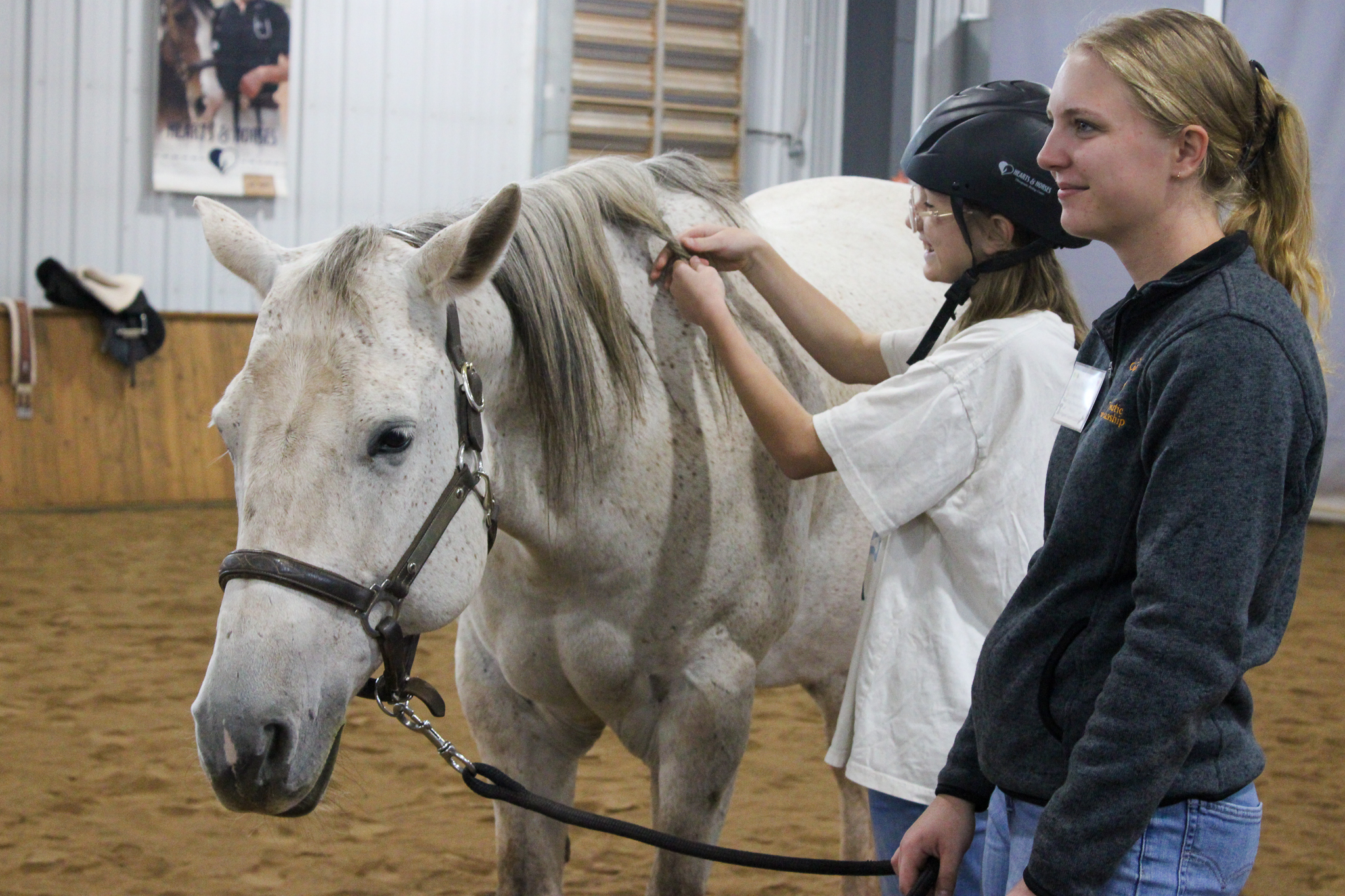 Image Claira Bothwell-Church braids the mane of her white horses during a Hearts & Horses Changing Leads session in October 2025.
