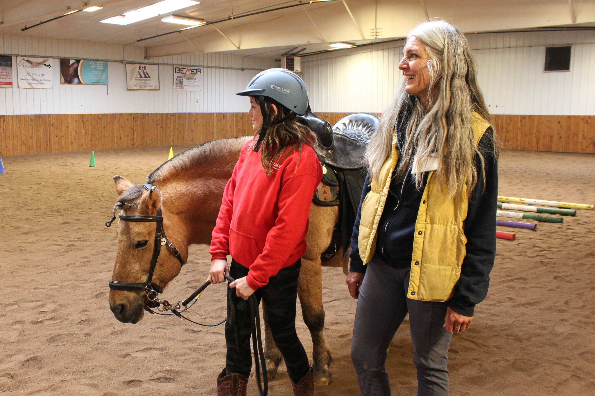 Image A young woman participant and adult volunteer walk with a horse during a session of Hearts & Horses Changing Leads program in October 2025.