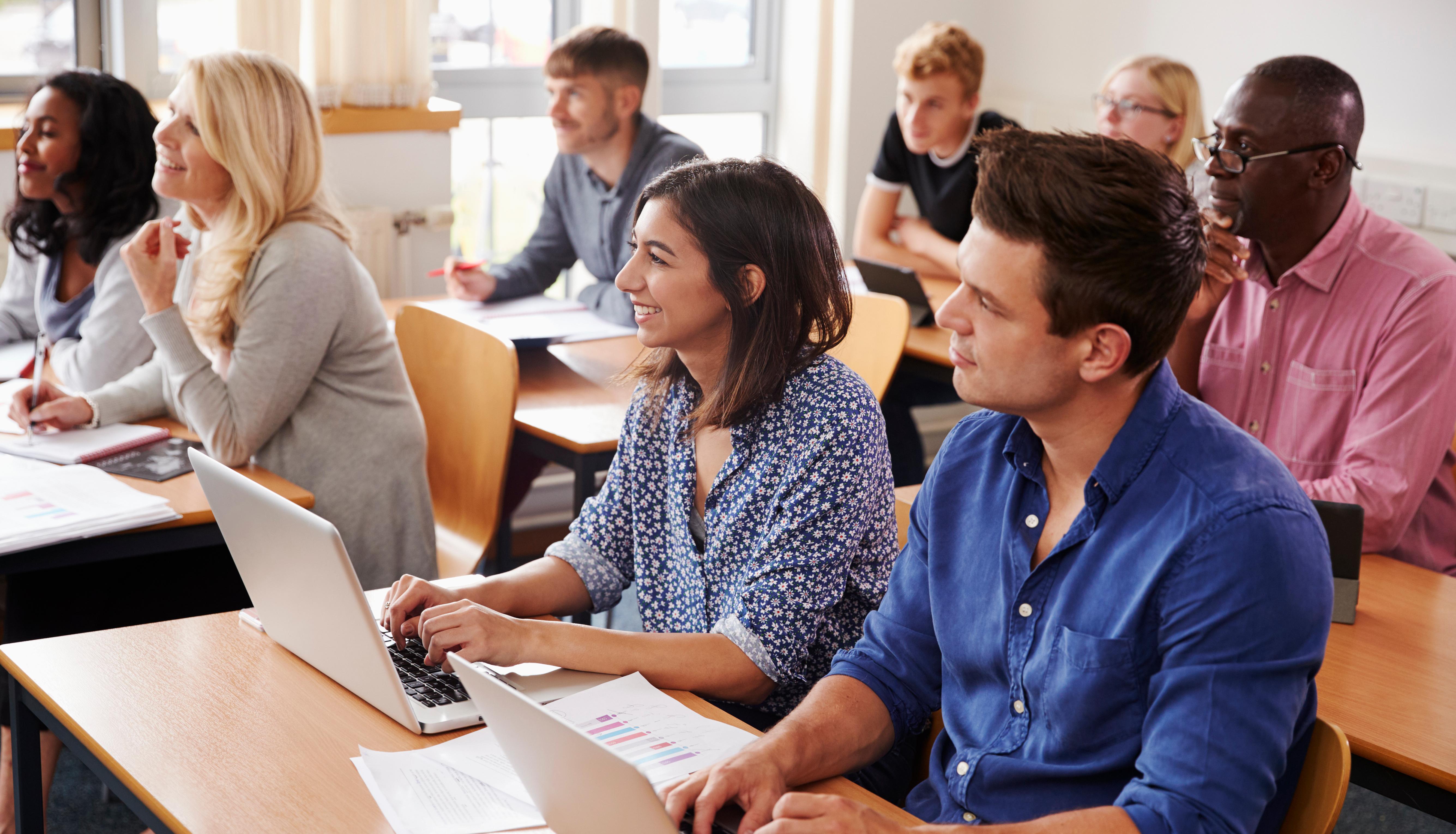 Adults sitting in conference room looking forward and taking notes