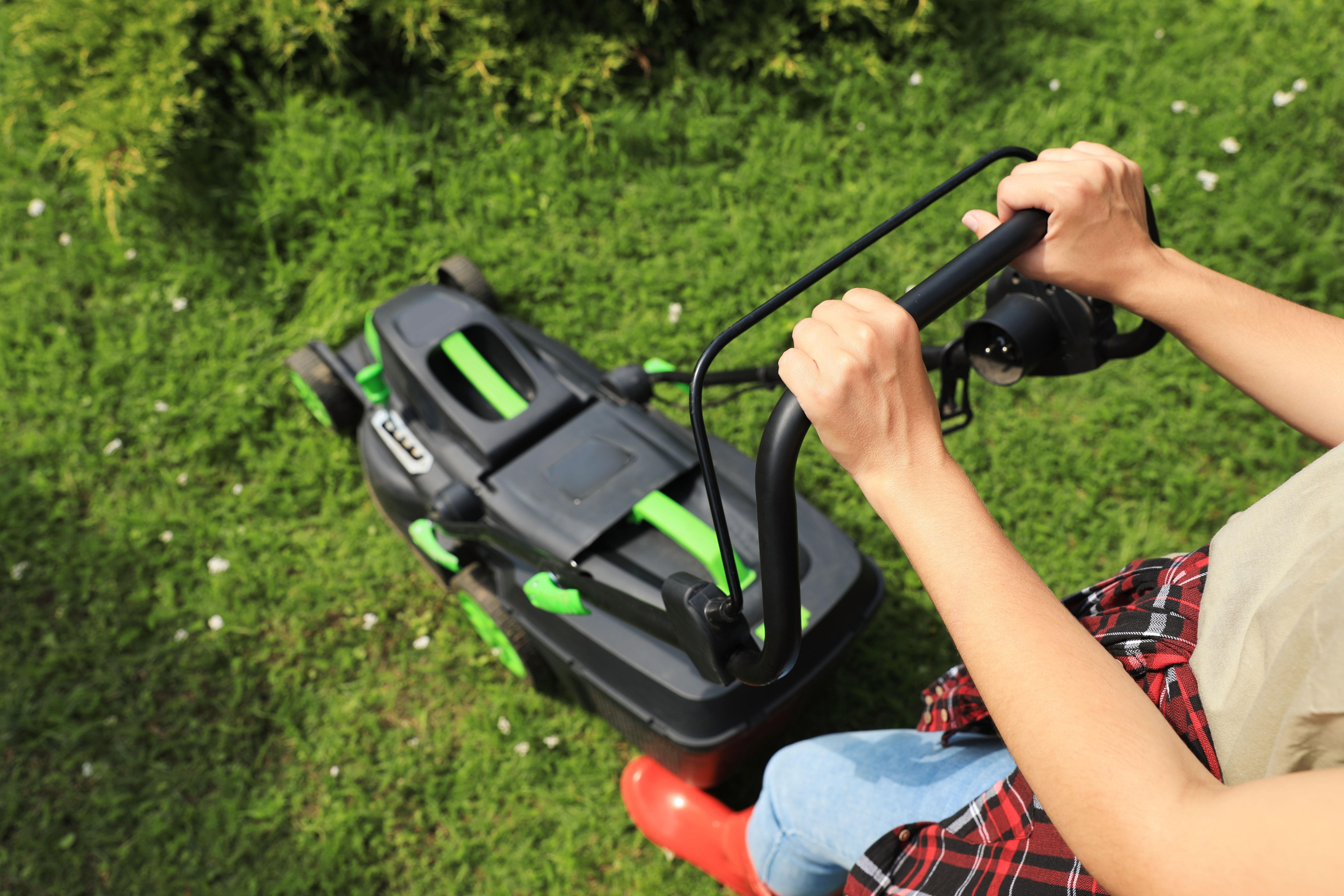 person pushing a mower in green grass