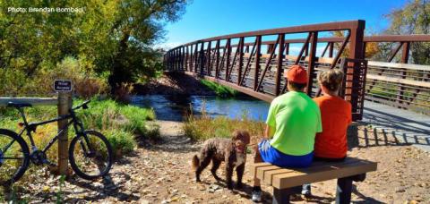 Two people sit on a bench at the Poudre River Trail