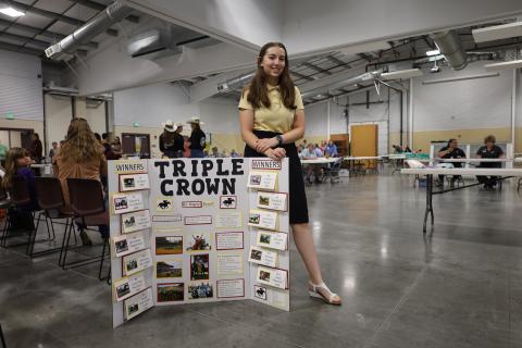 A 4-H member stands next to their Horseless Horse Project Poster at the Larimer County Fair