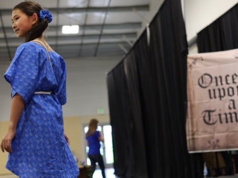 A 4-H member shows off the dress she made.  The dress is blue cotton with a dolman sleeve.