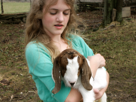A teenager holds her goat