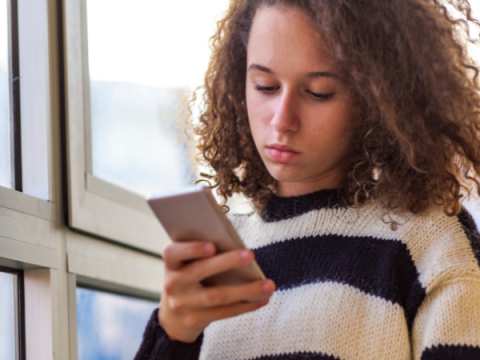 A teenager looks at their phone